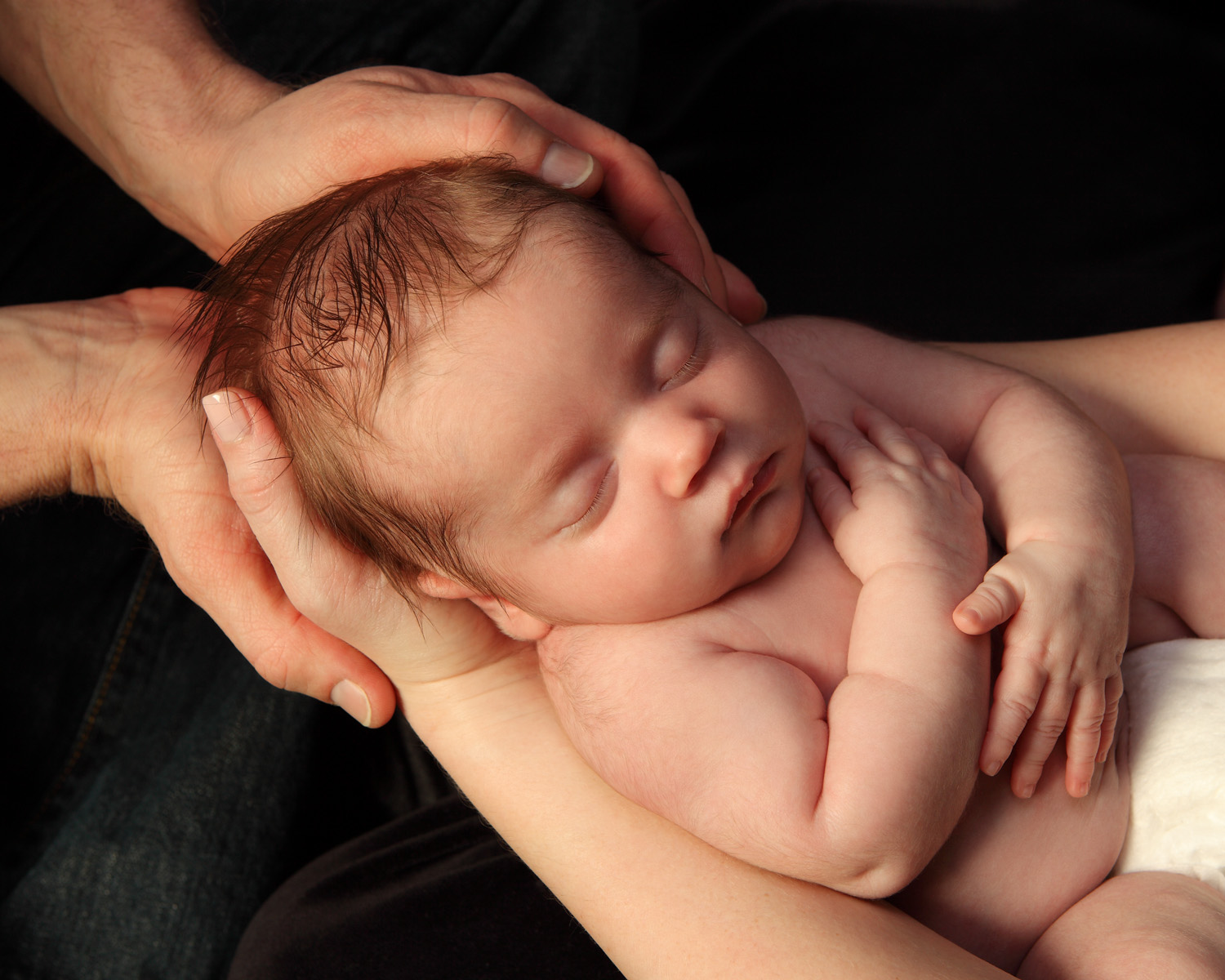 Sleeping newborn cradled in loving hands