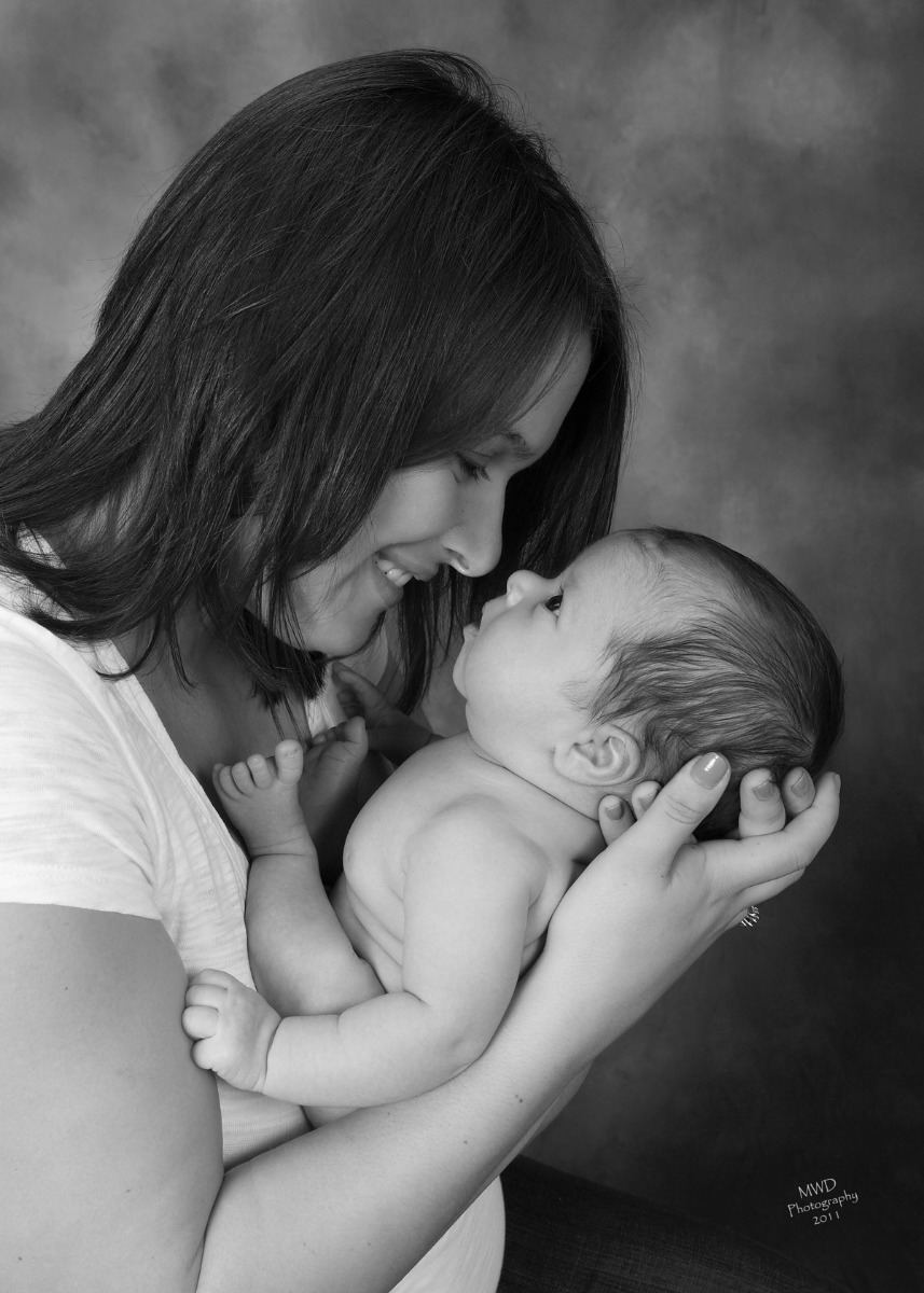 Mother cradling her newborn in a black-and-white portrait